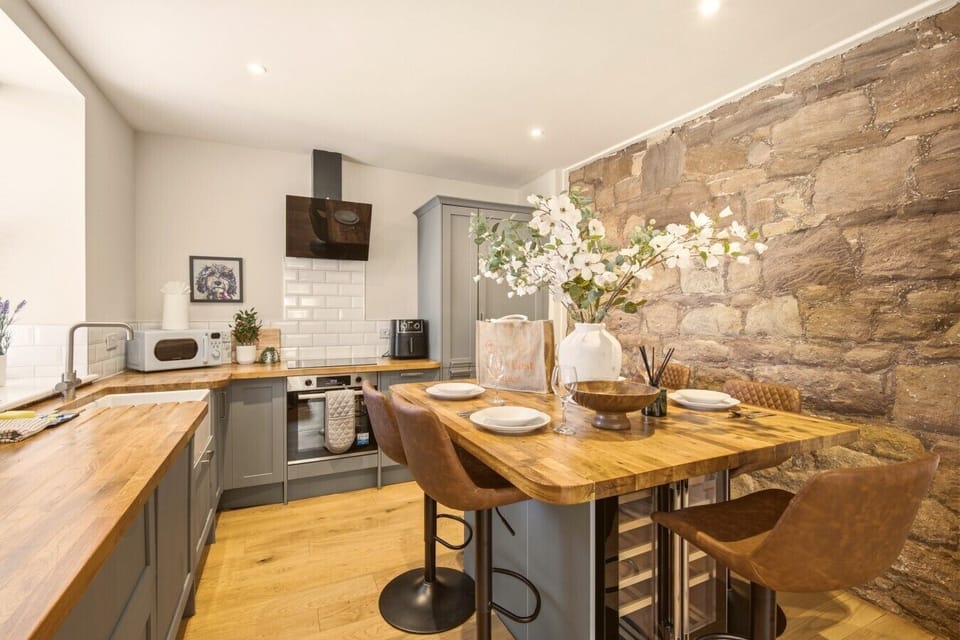 Kitchen and dining area with stone feature wall and breakfast bar.