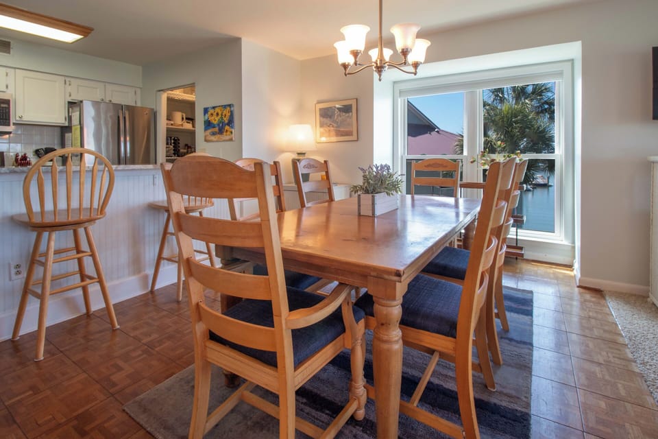 Gather around this welcoming dining table where meals become memories. Natural light fills the space from the patio doors, creating a warm and inviting atmosphere for your group.