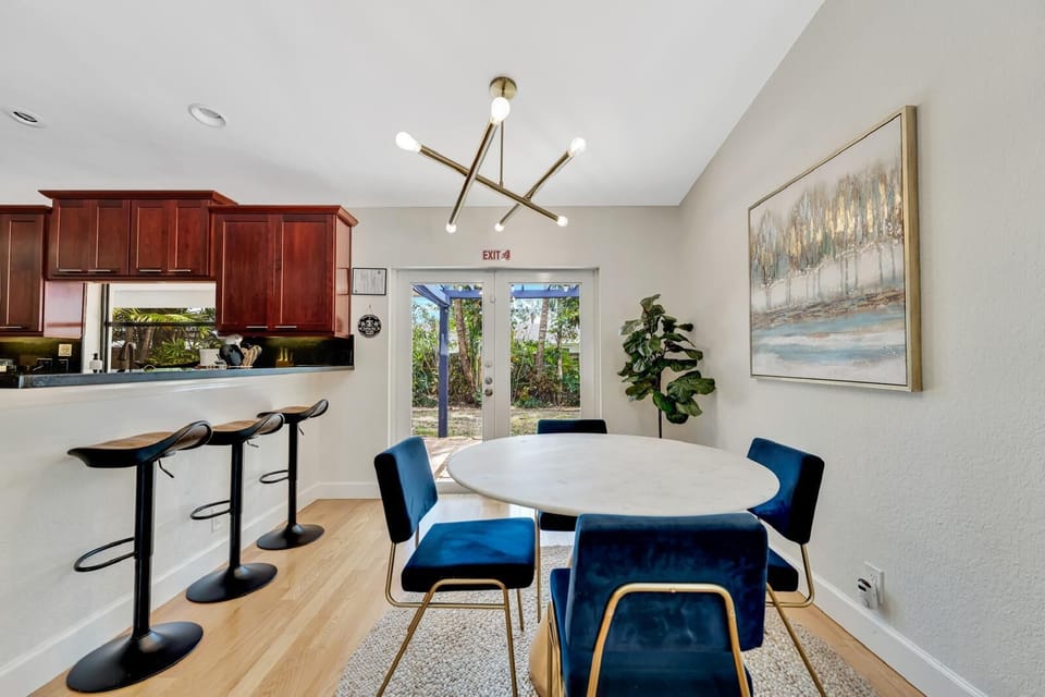 Modern dining area with blue velvet chairs & gold chandelier