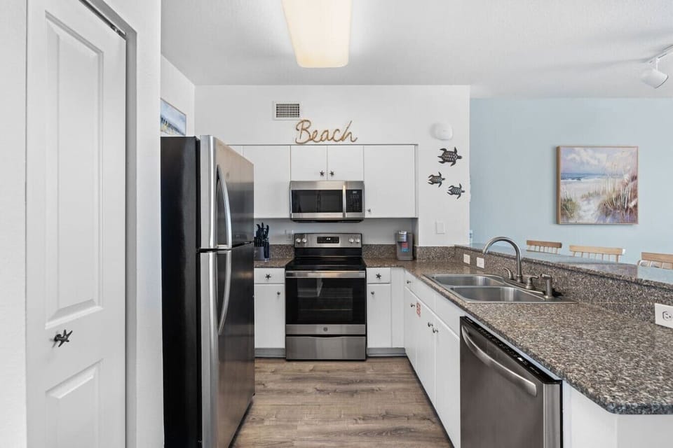 Fully equipped kitchen with stainless steel appliances and breakfast bar seating for easy meals after a day at the beach.