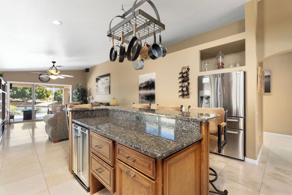 The expansive island with dual wine coolers and a hanging pot rack is the heart of the kitchen — perfect for entertaining while meals are being prepared.