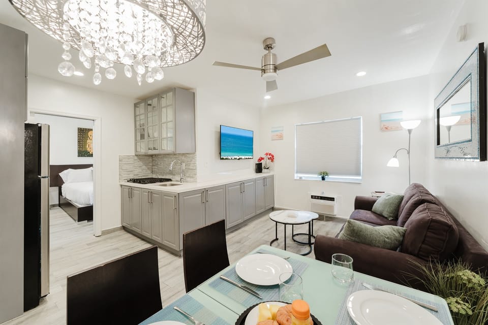 Bright, open-concept living space with a comfortable sofa, smart TV, and dining table for four—perfect for relaxing after a day at South Beach.