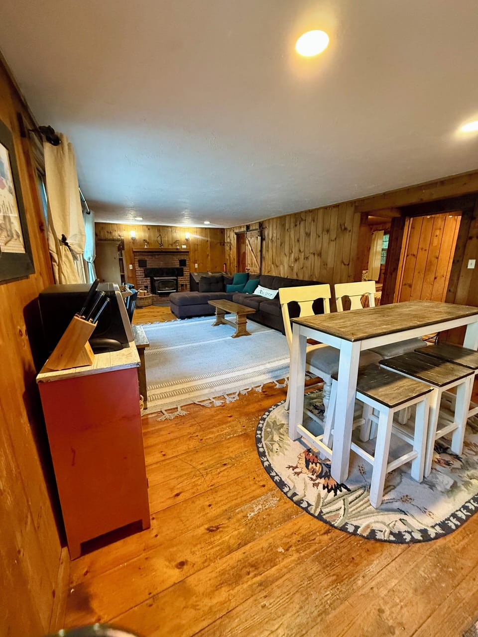 Relax in your spacious living and dining area with rustic wood paneling and cozy seating.