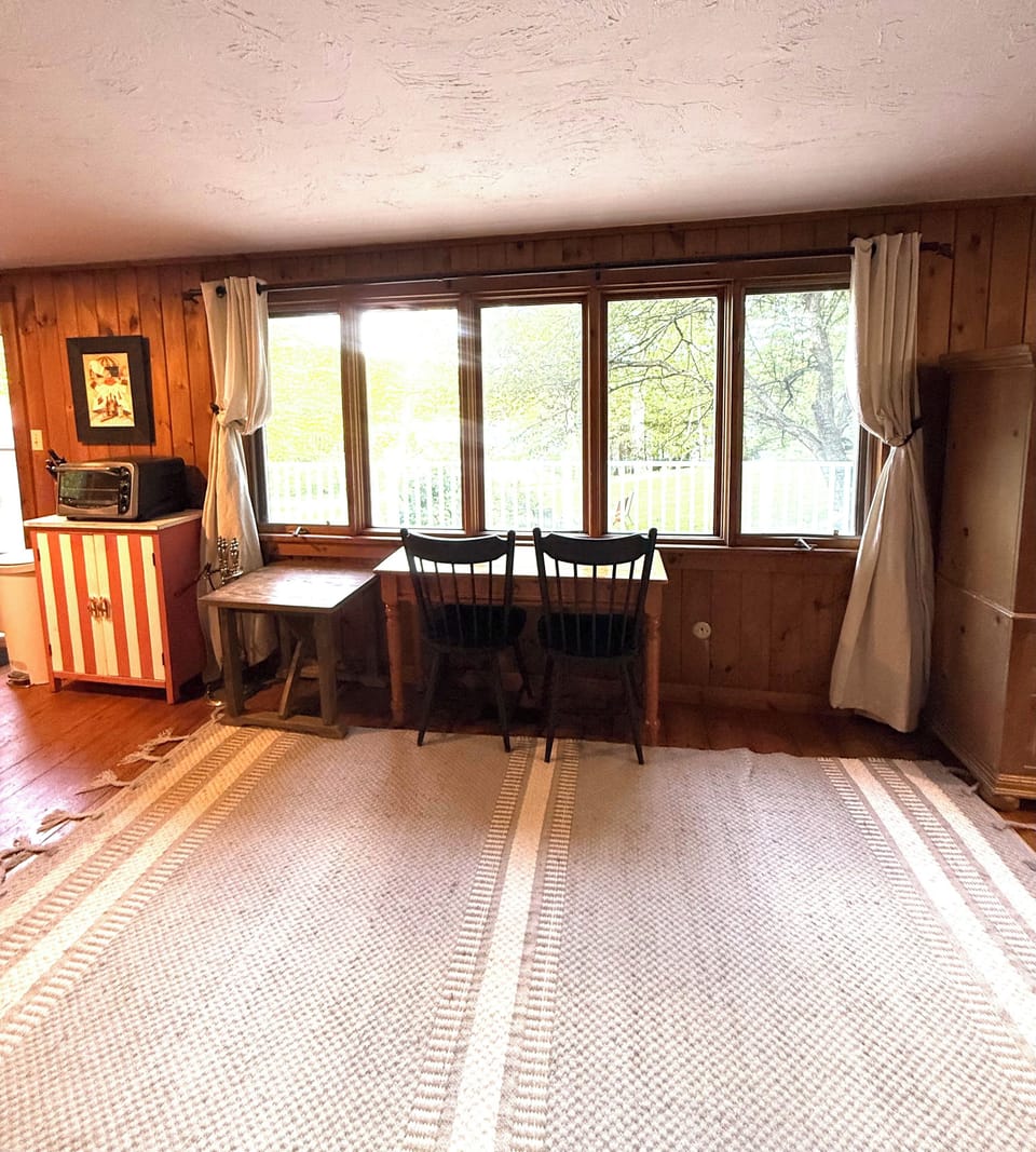 Gather around this cozy dining table and enjoy meals with natural light streaming through lakeside windows, framing your peaceful retreat.