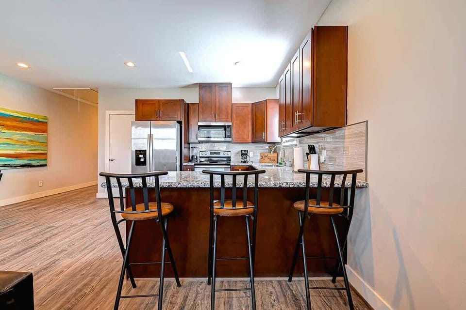 Modern kitchen with a large granite island and bar seating for three.