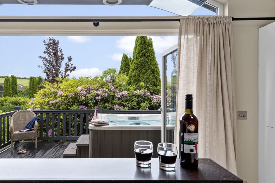 Kitchen leading to decking with hot tub and seating area - Brayford Lodge, Kentisbury Grange