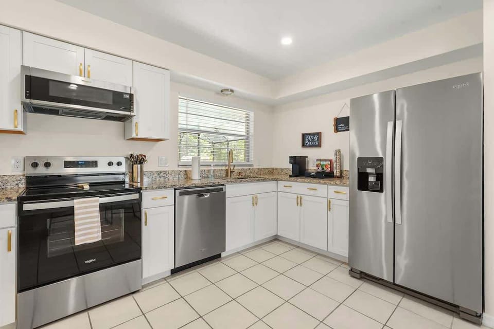 Bright open-concept kitchen featuring modern finishes, spacious countertops, stainless steel appliances, and everything needed for cooking family meals, team dinners, and extended Disney-area stays in this luxury Kissimmee vacation home.
