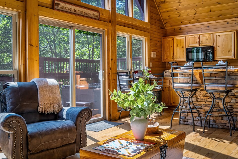 Sunlit log cabin with forest views, rustic charm, and cozy bar seating