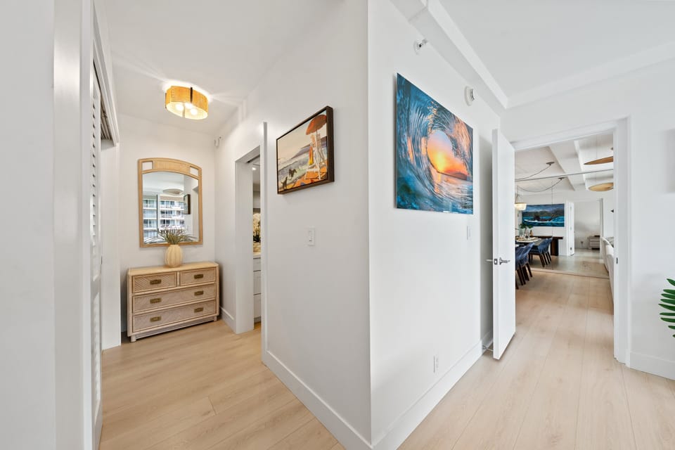 Welcoming entry hallway with warm lighting, coastal artwork, and a clear path into the main living space.