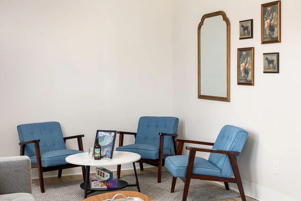 Cozy sitting nook with blue accent chairs, games, and welcoming touches for relaxed conversation.