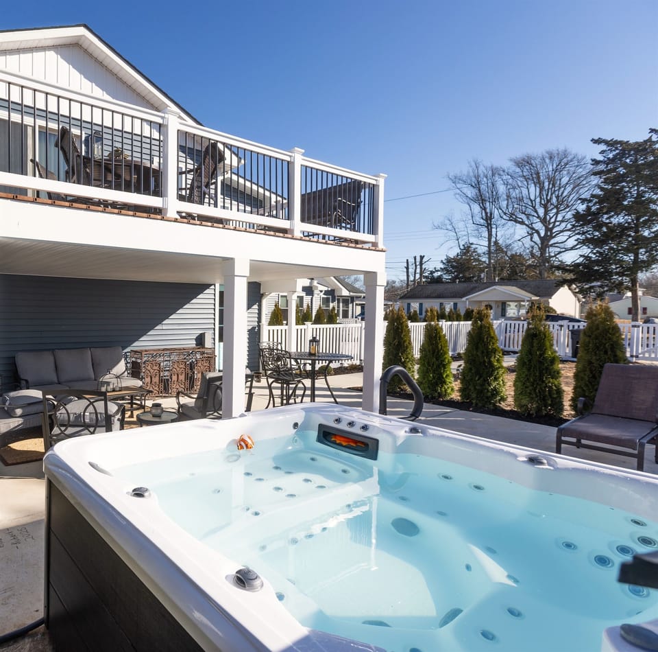 Private hot tub with covered patio seating beneath the elevated deck