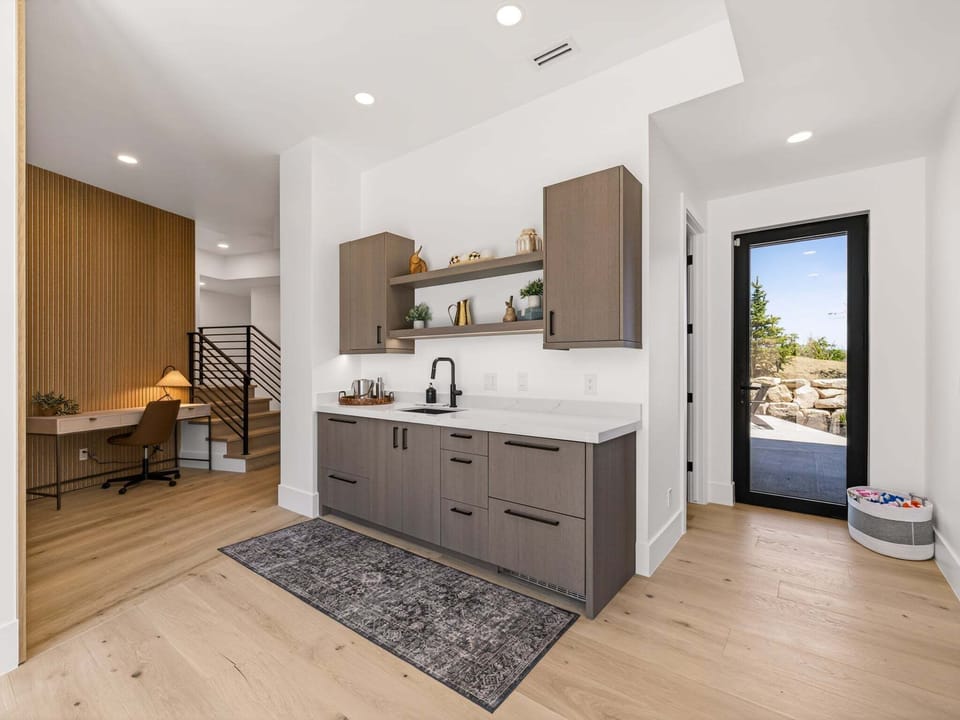 A small kitchenette with dishwasher, sink and supplies for outdoor entertainment await downstairs near the lower deck entrance.