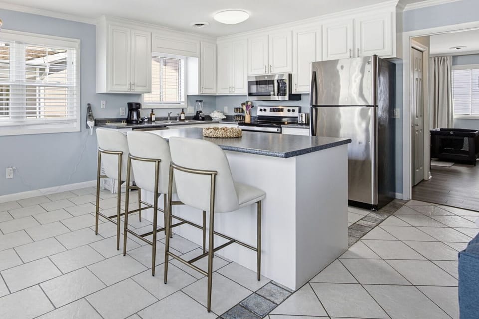 Fully equipped kitchen with bar seating, stainless steel appliances, and everything you need to cook at home