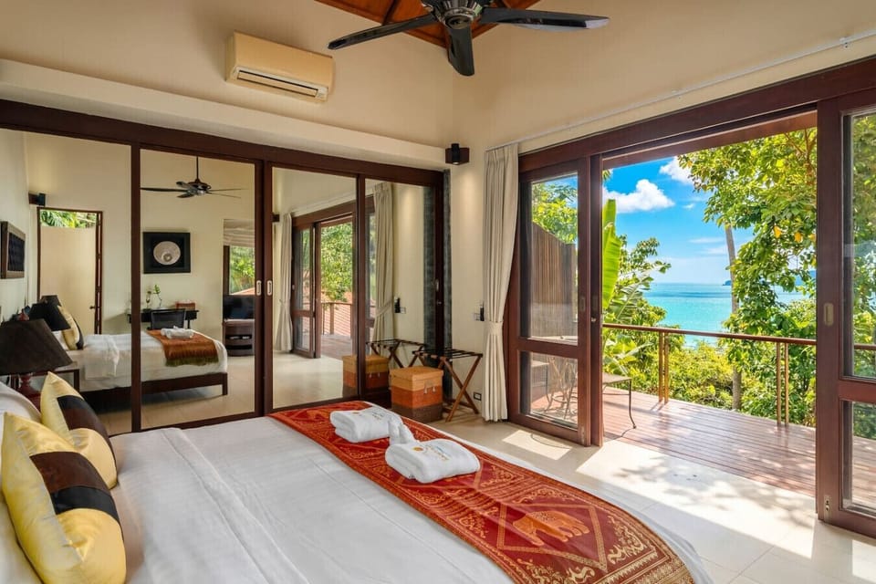 Comfortable lounging area in Bang Kao rental with designer furniture panoramic doors and lush jungle surroundings