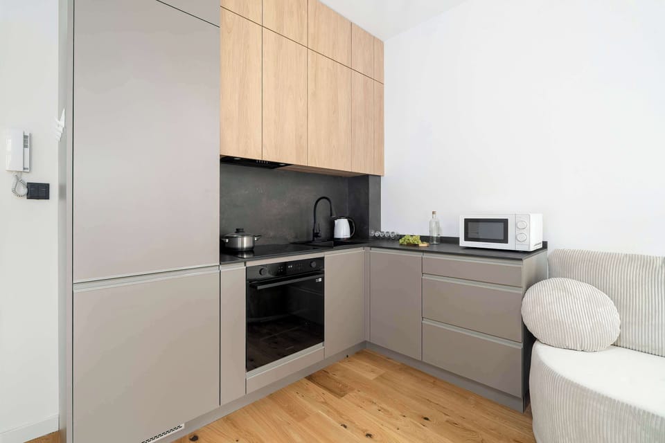 A compact kitchen includes light wood cabinets, built-in appliances, and sleek storage units. The clean design maximizes efficiency in a small space.