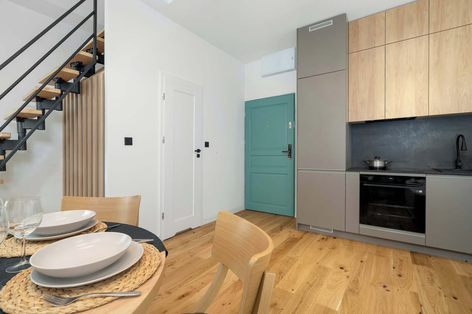 A kitchen and dining perspective reveals cabinets beneath a staircase and a table prepared for meals. The integrated design uses space efficiently.