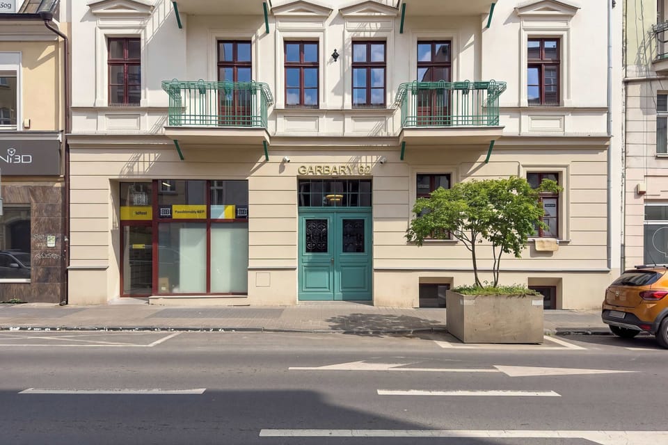 A street-level exterior view shows a row of buildings with shops and apartments above. Cars and sidewalks create an urban atmosphere.