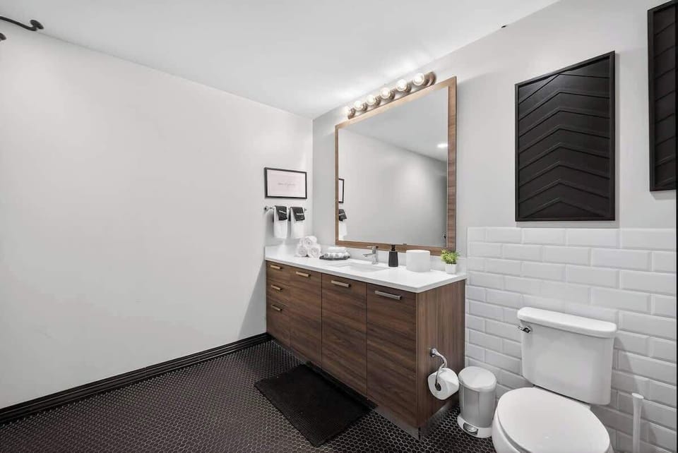 Modern vanity with warm wood tones and fresh towels - hotel-quality restocking before every stay in the Jazz Loft.