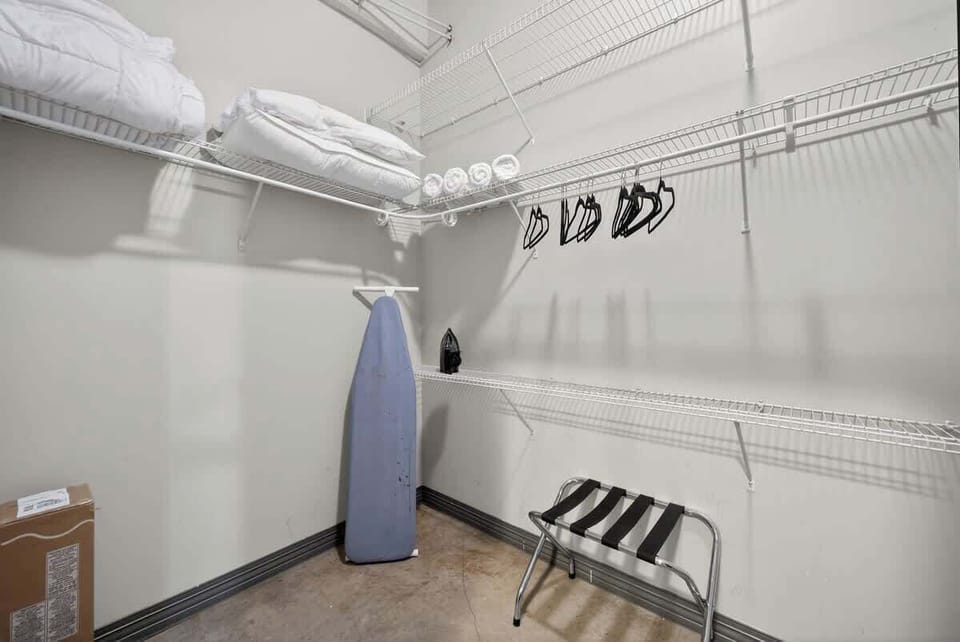 Spacious walk-in closet with hanging storage, extra linens, and foldable Pack 'n Play for families traveling with infants.