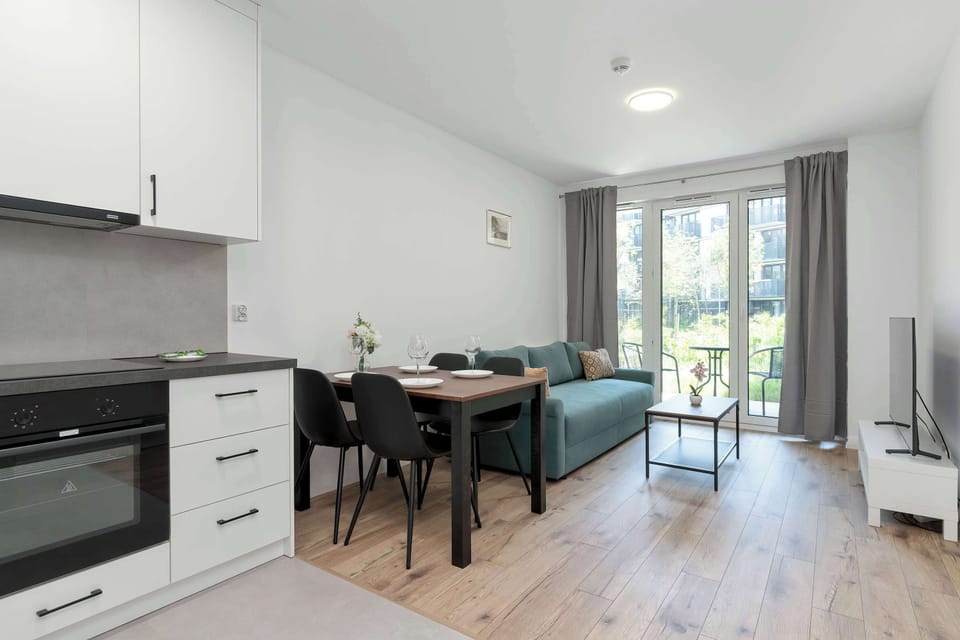 An open kitchen combined with a dining and living space. The layout feels spacious and bright with large windows and light wood flooring.