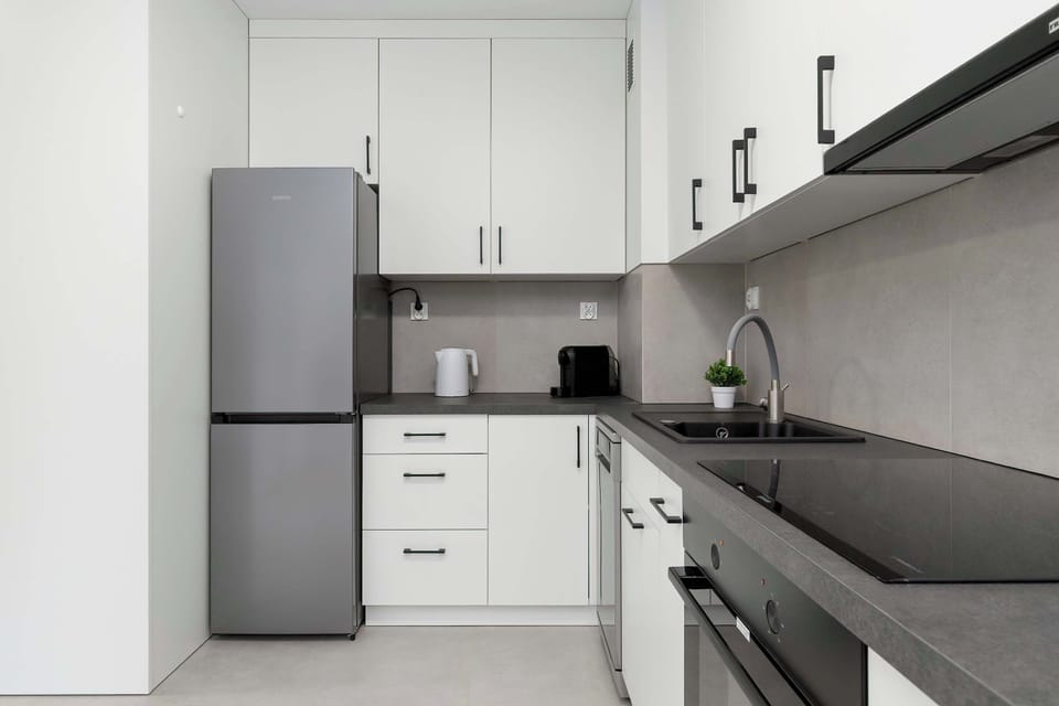 A close-up view of a kitchen corner with sleek cabinets and countertops. The design emphasizes simplicity and modern finishes.