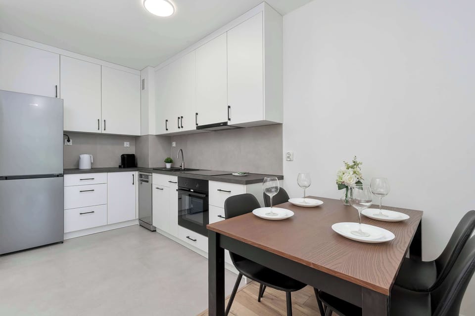 A clean, modern kitchen with white cabinetry and built-in appliances. The design is minimal and practical, with a focus on efficiency.