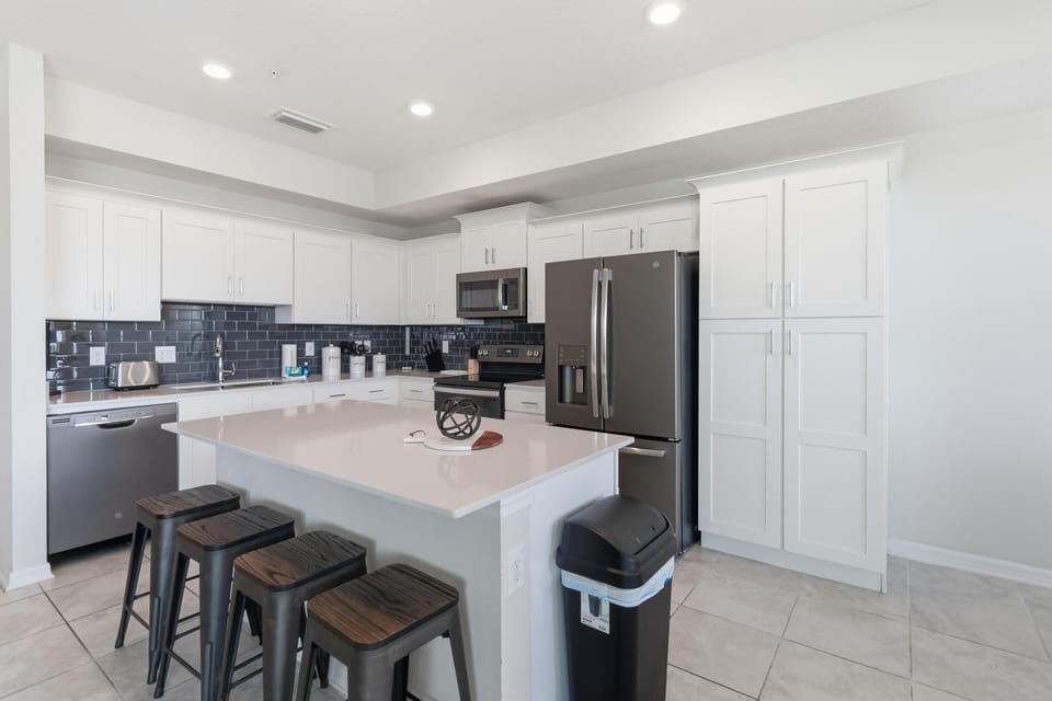 White shaker cabinets contrast with glossy dark subway tile backsplash in the bright kitchen area.
