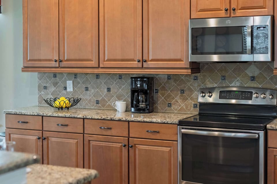 Kitchen area with granite countertops, wooden cabinets, and stainless steel appliances