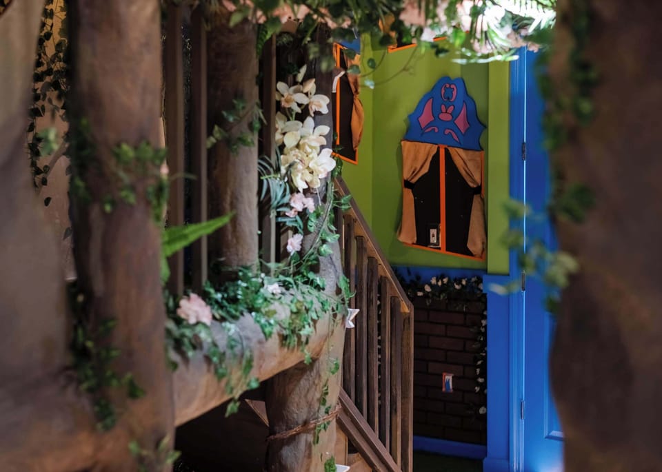 Rustic hallway decorated with greenery and floral accents leading to a colorful door.