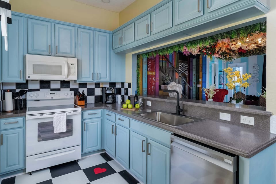 Bright kitchen with blue cabinetry and a checkered floor featuring a red heart accent.