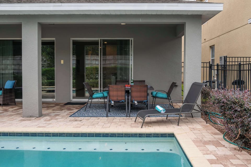 Covered patio dining area with poolside lounge chairs for relaxing.