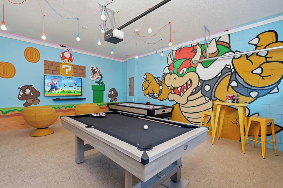 Game room featuring a pool table, air hockey, and Super Mario-themed wall art for family-friendly fun.