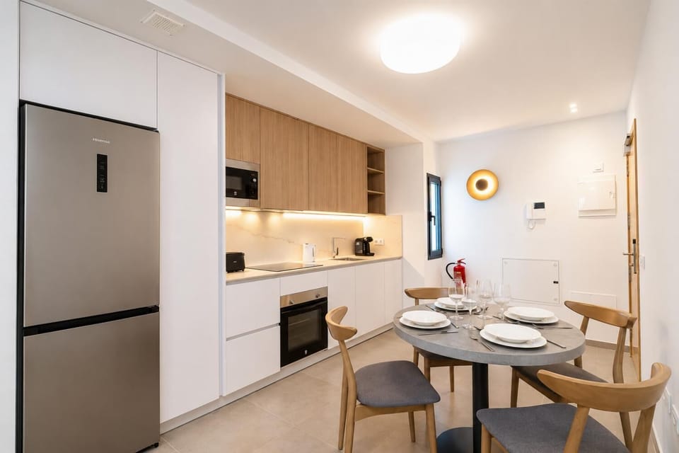 Modern open-plan kitchen and dining area with warm wooden cabinetry and a stylish table setting.