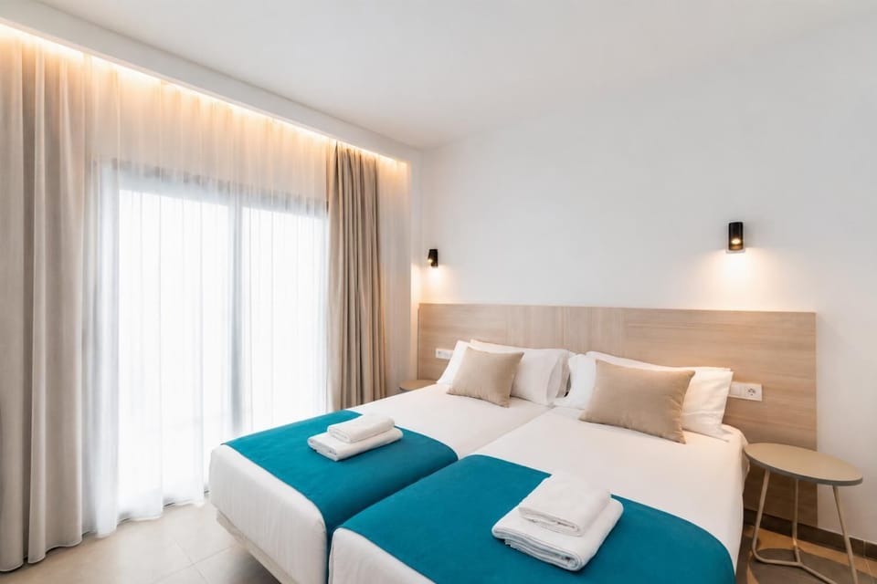 Bright twin bedroom with soft neutral tones, and warm natural light.