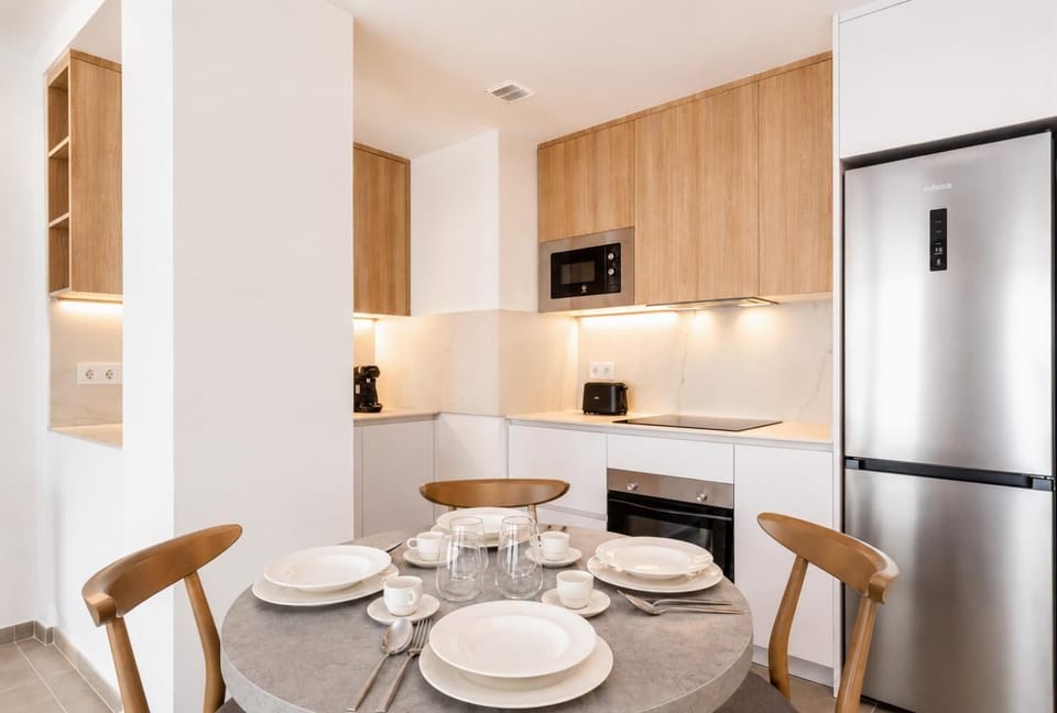 Modern open-plan kitchen and dining area with warm wooden cabinetry and a stylish table setting.