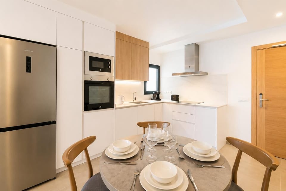 Modern open-plan kitchen and dining area with warm wooden cabinetry and a stylish table setting.
