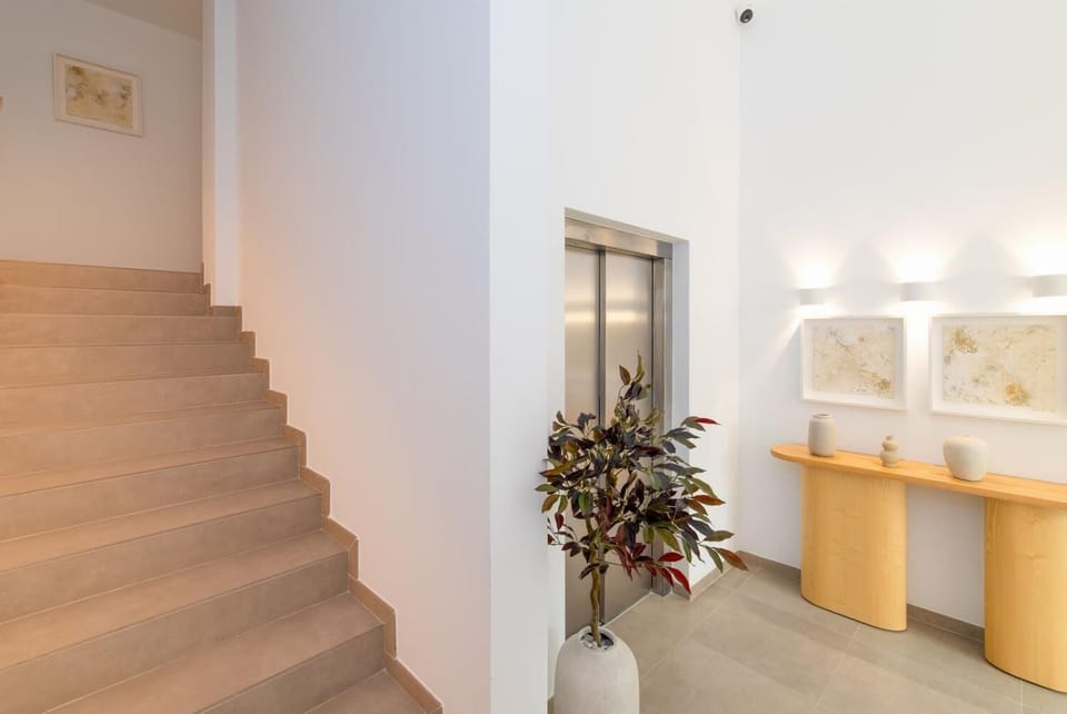 A bright modern lobby with a staircase, elevator, and elegant minimalist decor.