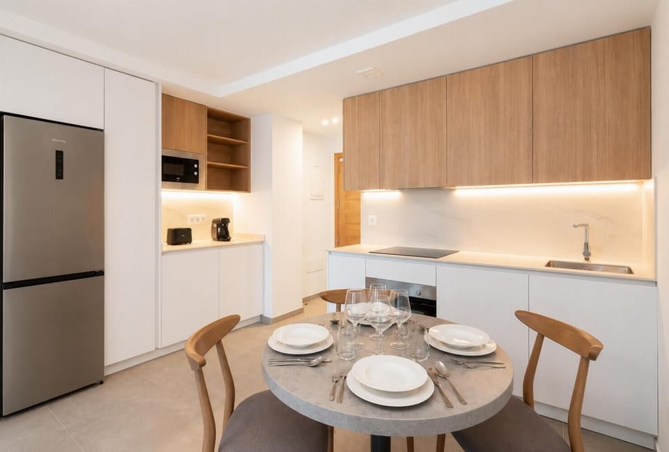 Modern open-plan kitchen and dining area with warm wooden cabinetry and a stylish table setting.