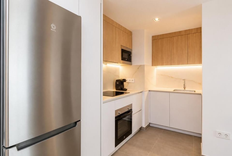 Modern open-plan kitchen and dining area with warm wooden cabinetry and a stylish table setting.