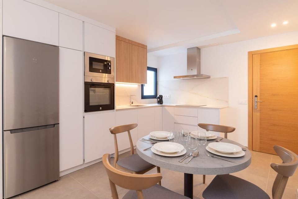 Modern open-plan kitchen and dining area with warm wooden cabinetry and a stylish table setting.