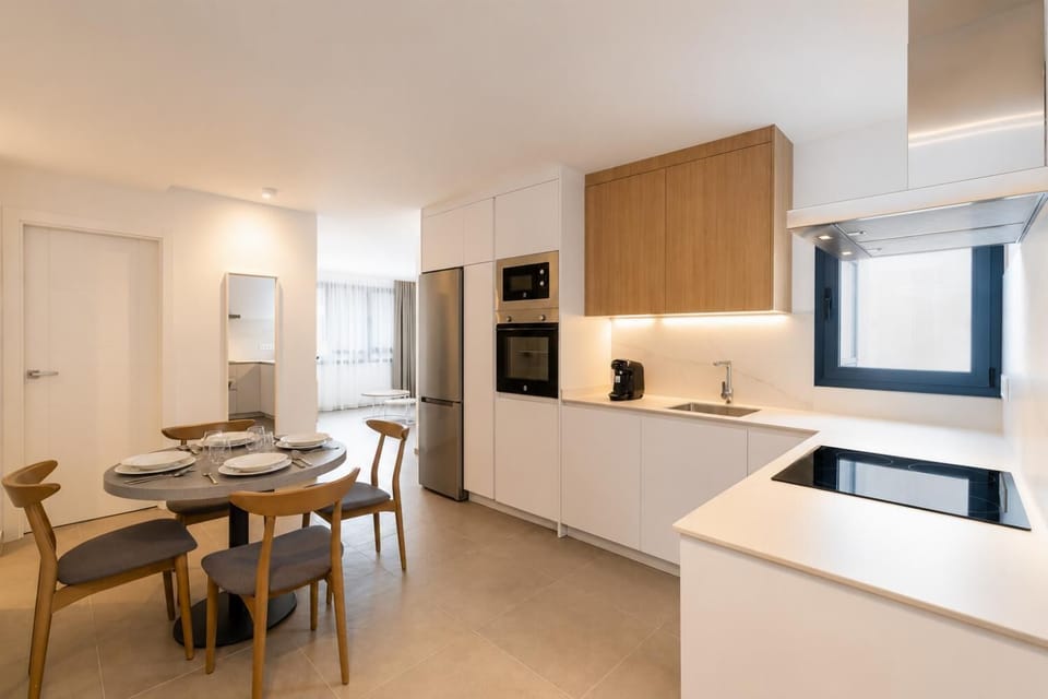 Modern open-plan kitchen and dining area with warm wooden cabinetry and a stylish table setting.