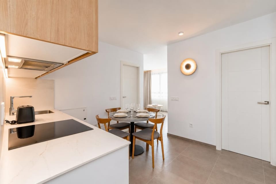 Modern open-plan kitchen and dining area with warm wooden cabinetry and a stylish table setting.