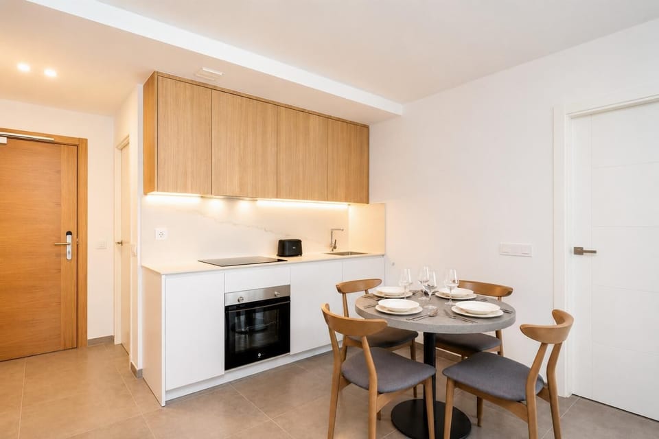 Modern open-plan kitchen and dining area with warm wooden cabinetry and a stylish table setting.