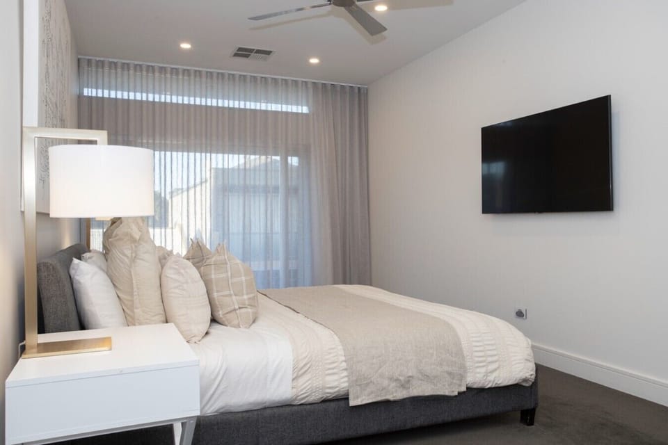 King master with wall-mounted TV and sheer drapes