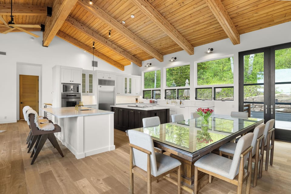 Open concept dining and kitchen with tongue-and-groove ceilings throughout and access to both the back and front deck spaces.