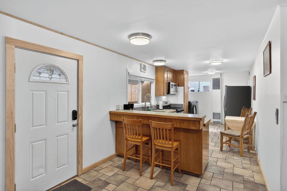 Cook and socialize with ease in this functional space featuring warm wood cabinetry and a convenient bar counter. The open layout seamlessly connects the kitchen to the dining and living areas, keeping your whole crew together.