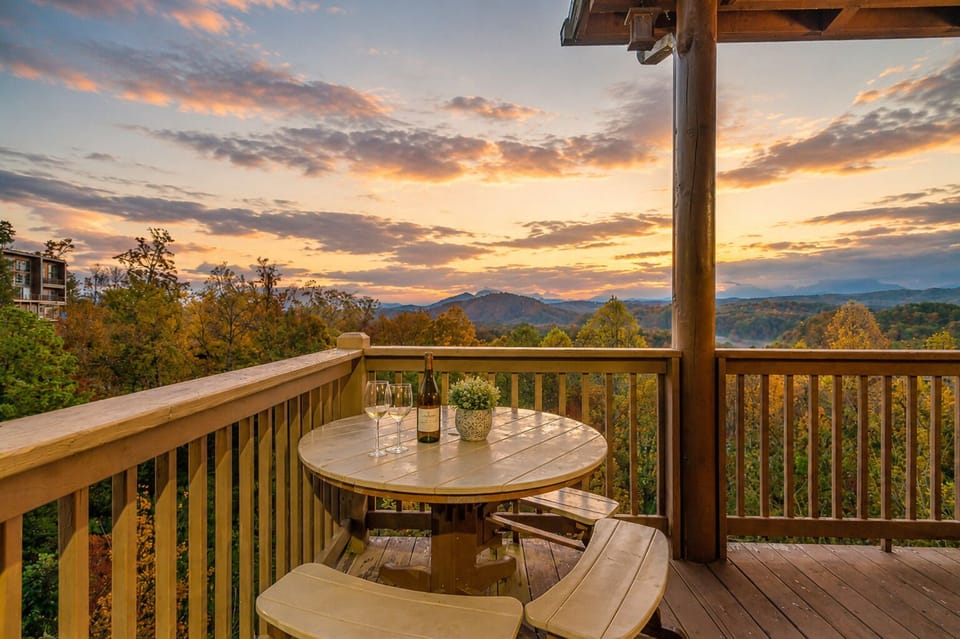 Scenic outdoor dining area with mountain sunset views and covered deck seating, perfect for relaxing mornings or evening gatherings in the Smokies.