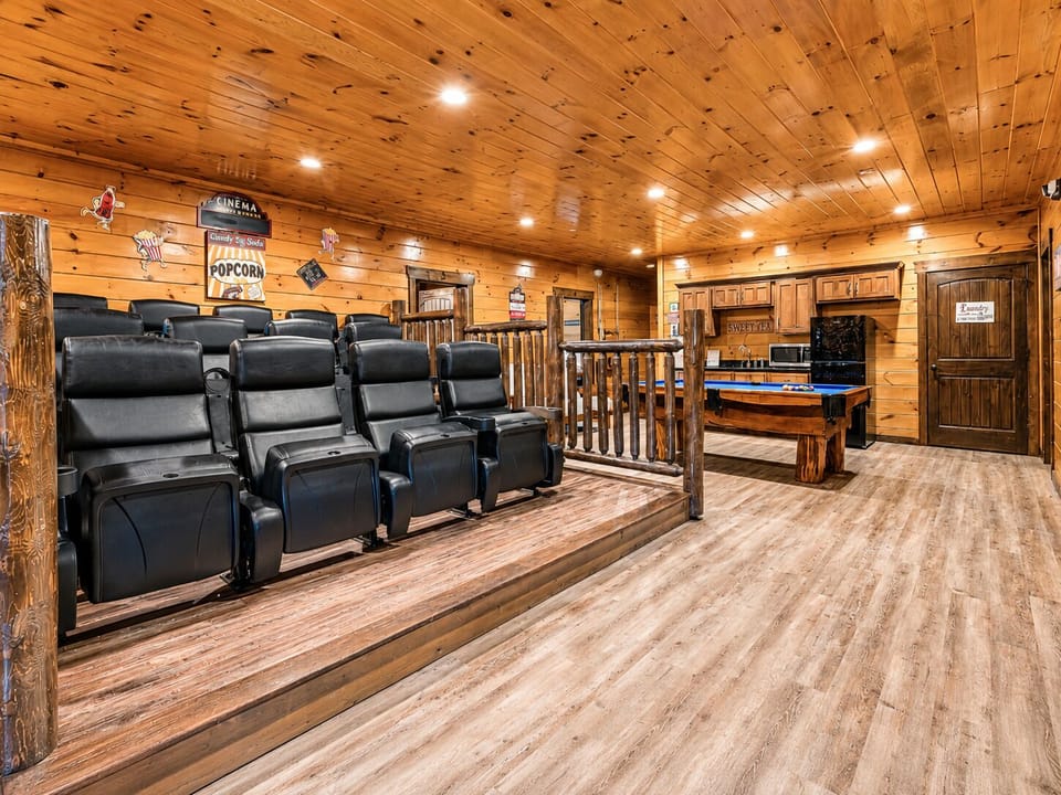Large entertainment loft combining leather theater seating, a pool table, kitchenette appliances, rustic décor, and open space for family and group activities.