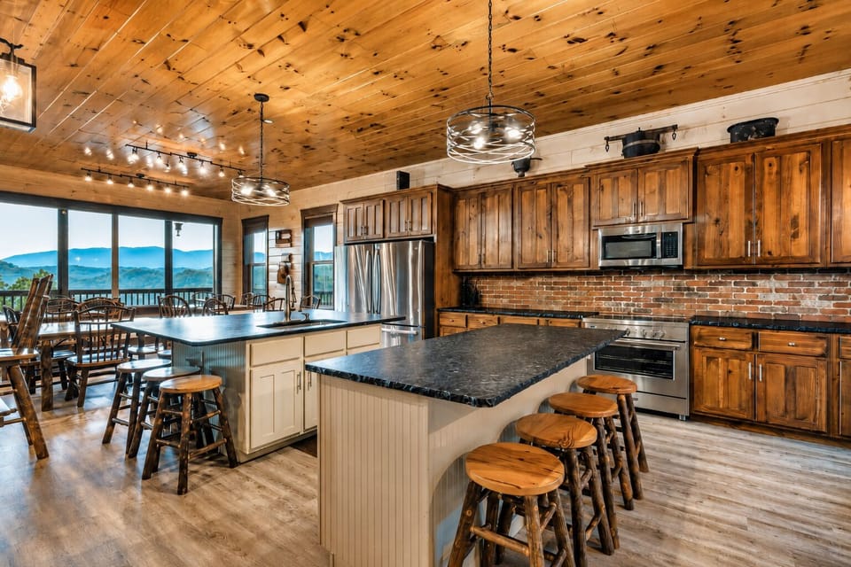 Full cabin kitchen with granite countertops, stainless-steel refrigerator, range, microwave, custom wood cabinets, large island, and breakfast bar seating.