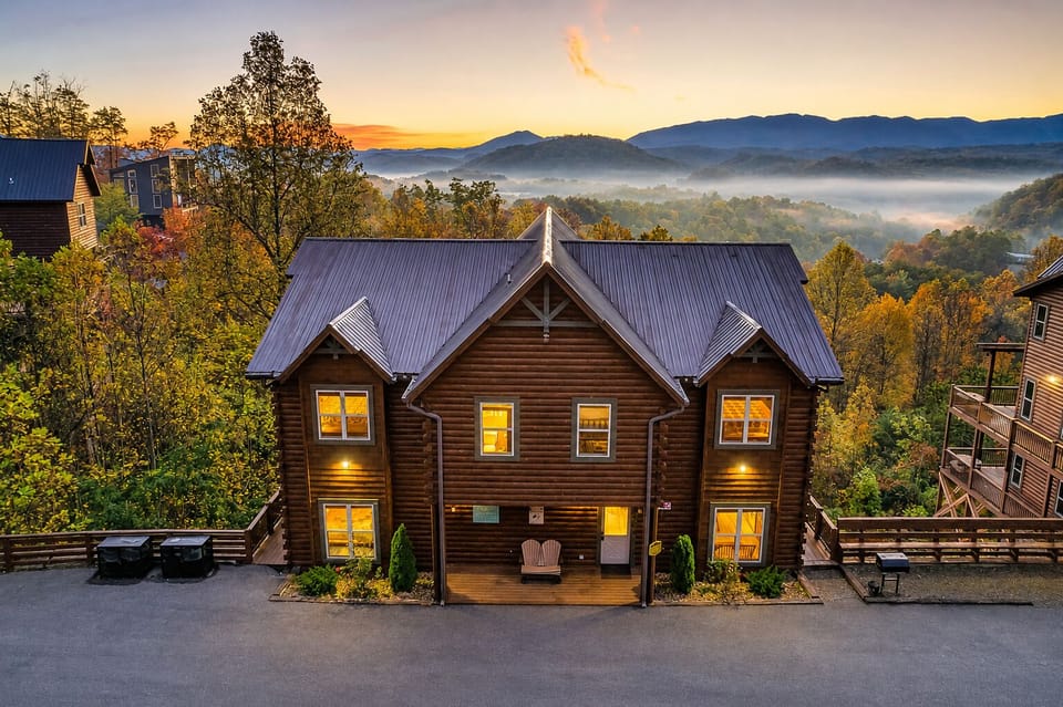 Luxury Smoky Mountain cabin exterior at sunset with panoramic mountain views, multi-level decks, modern rustic design, and spacious group lodging in Sevierville, Tennessee.
